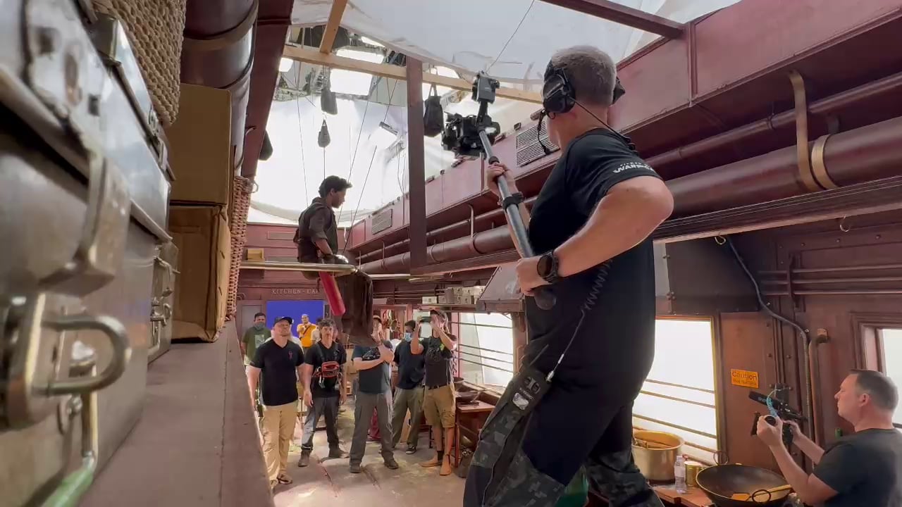 Hyper-WarpCam® operator holding the pole-mounted camera beside a performer on an interior action set.